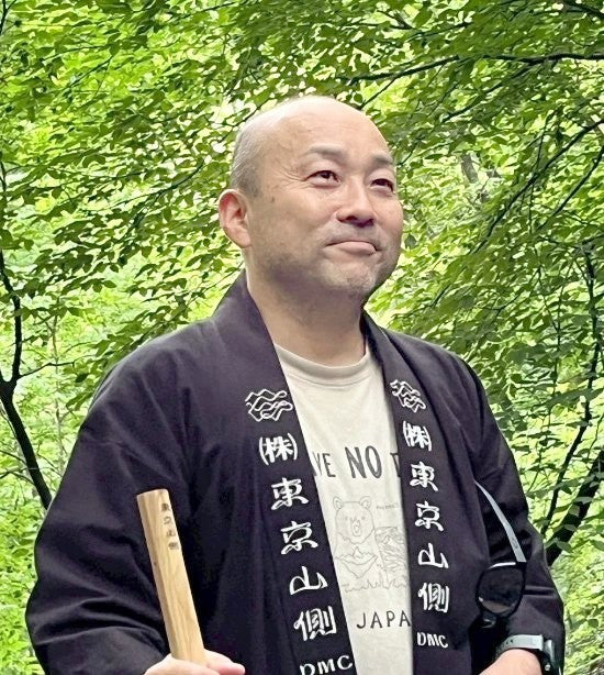 東京山側DMCの法被を着て森に立つ代表取締役 宮入正陽