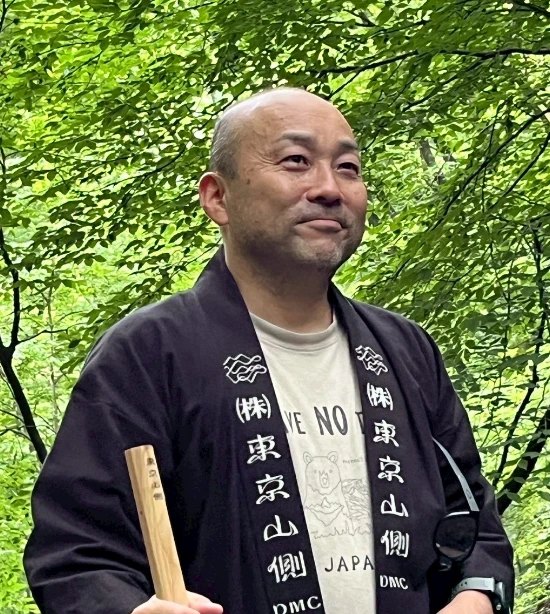 東京山側DMCの法被を着て森に立つ代表取締役 宮入正陽